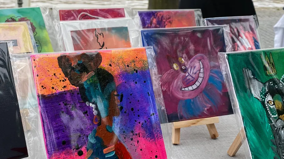 Colorful paintings displayed on easels outdoors.