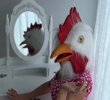 Person in chicken mask posing by mirror.