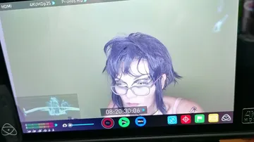 Person with glasses on monitor screen.