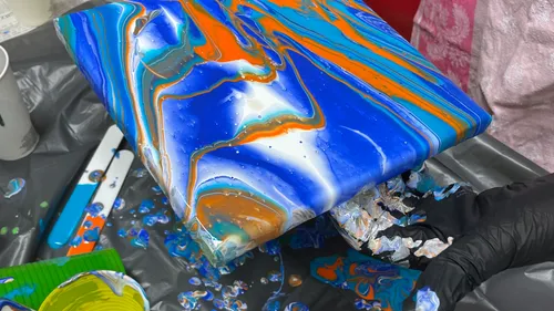 Leinwand mit blauer und orangener Farbwirbelung.