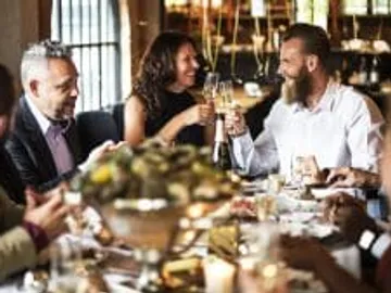Friends toast with glasses in a festive restaurant.