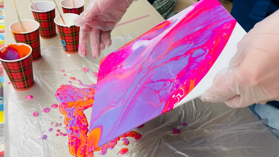 Hand tilting canvas for acrylic pour painting.