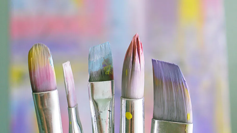 Paintbrushes with colorful bristles, blurred background.