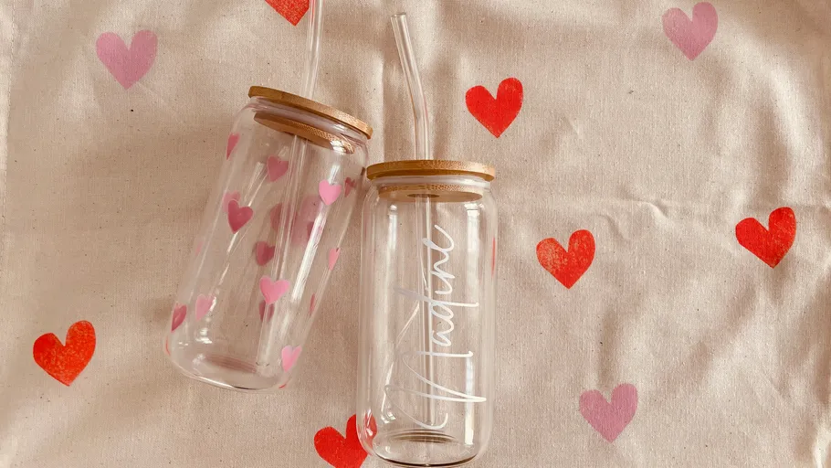 Zwei Glasflaschen mit Herzdesigns auf Stoff.