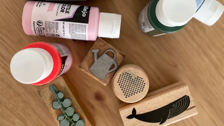 Paint bottles and stamps on wooden table.