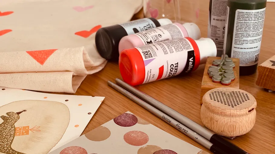 Art supplies on wooden table, including paint bottles.