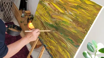Person painting abstract art on canvas indoors.
