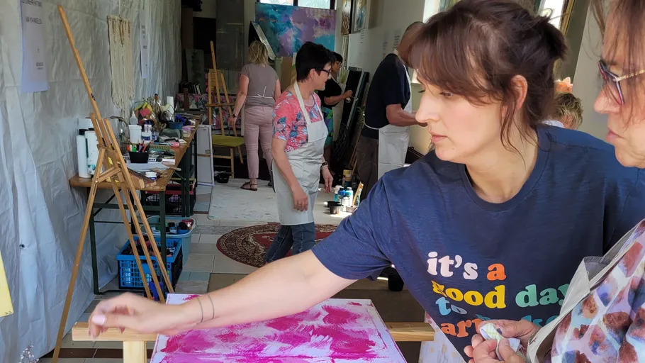 Woman painting in art studio with others.