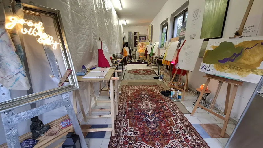 Art studio with paintings on easels and rugs.