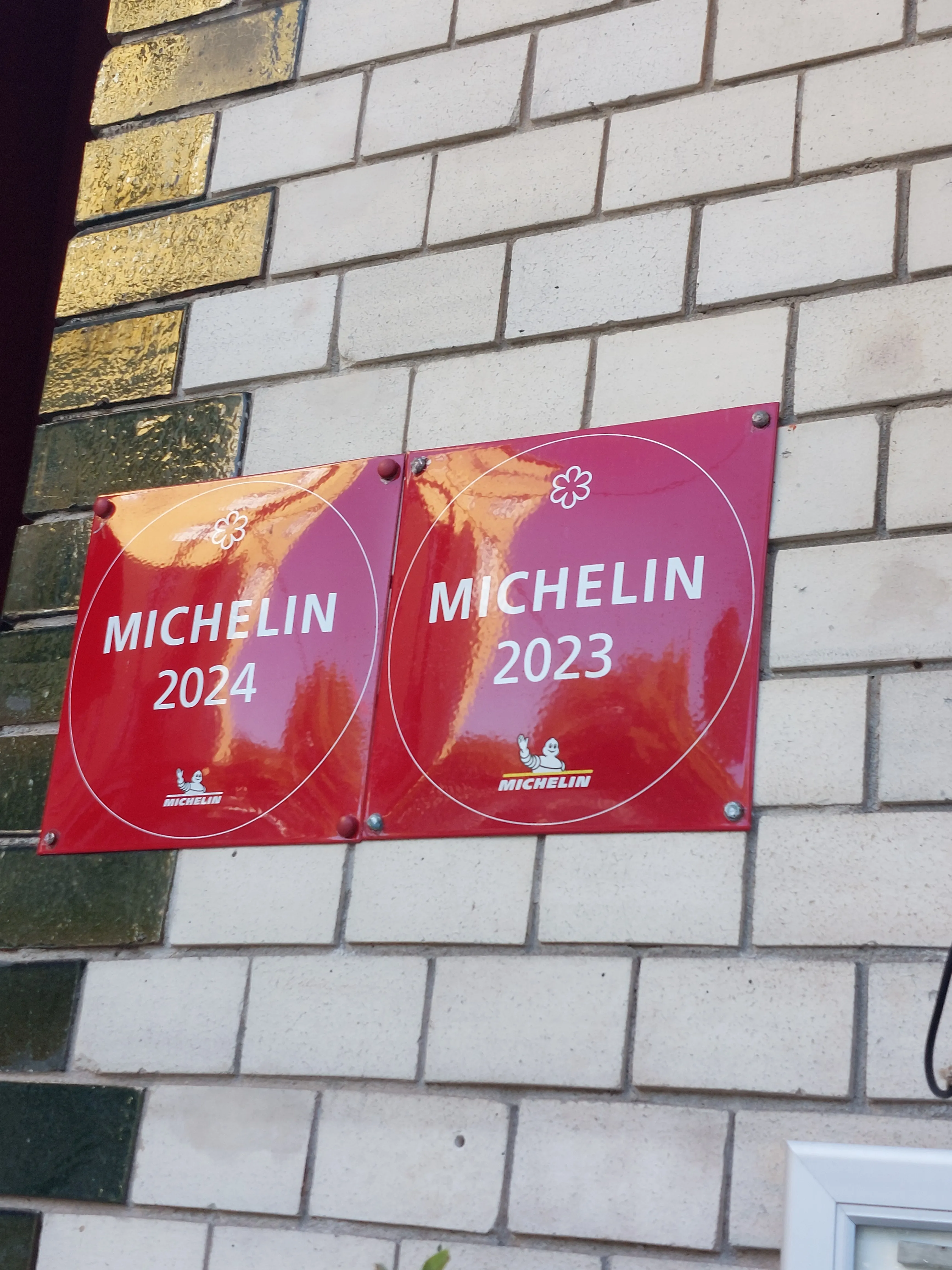 Two Michelin signs on a brick wall.