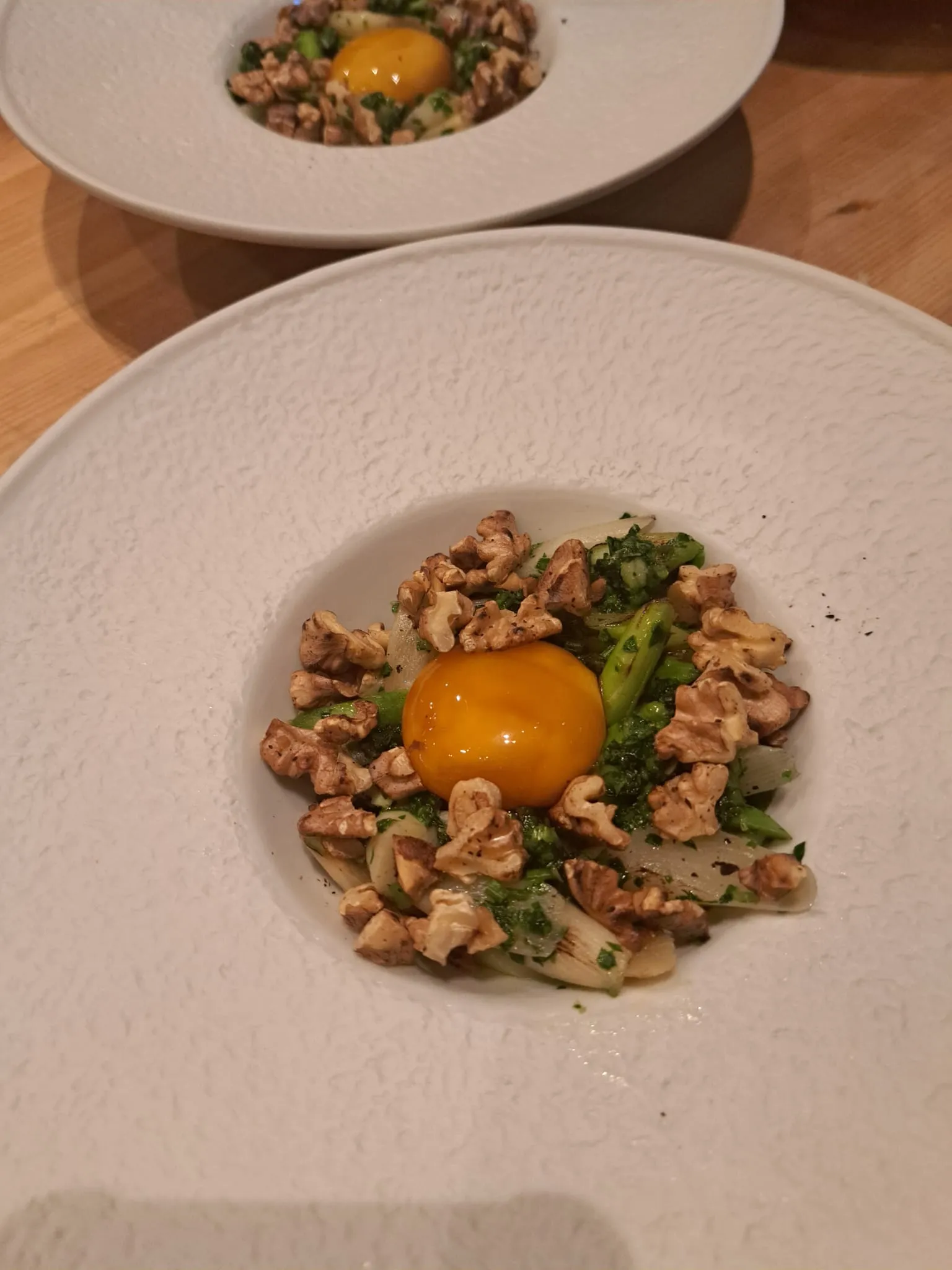 Egg yolk, walnuts on vegetable garnish, white plate.