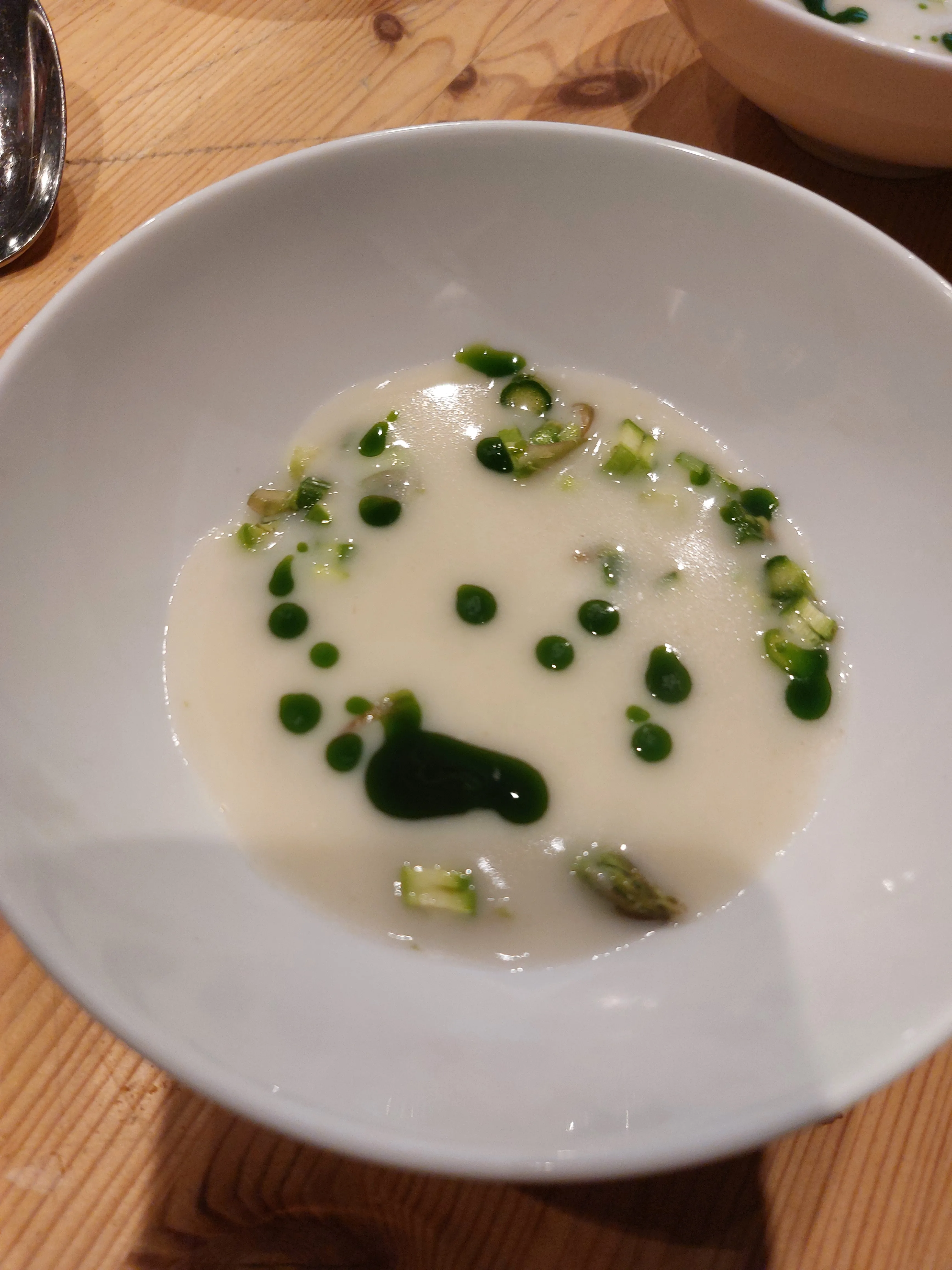 White soup with green garnish in a bowl.