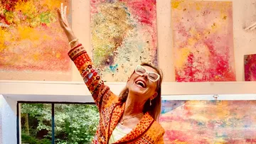 Frau posiert freudig in farbenreicher Kunstgalerie.