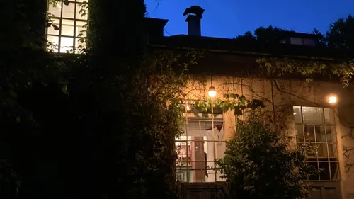 Haus mit Efeu und beleuchteten Fenstern abends.