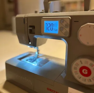 Nähmaschine zeigt Einstellungen in Werkstatt.