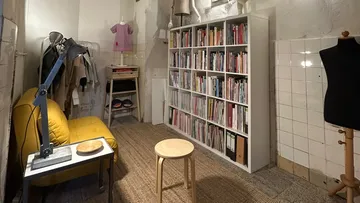 Gemütlicher Raum mit Bücherregal und Schaufensterpuppen.
