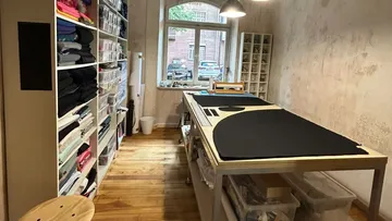 Sewing room with shelves and cutting table.