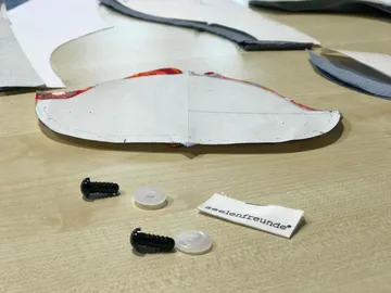 Fabric pieces and screws on a table.