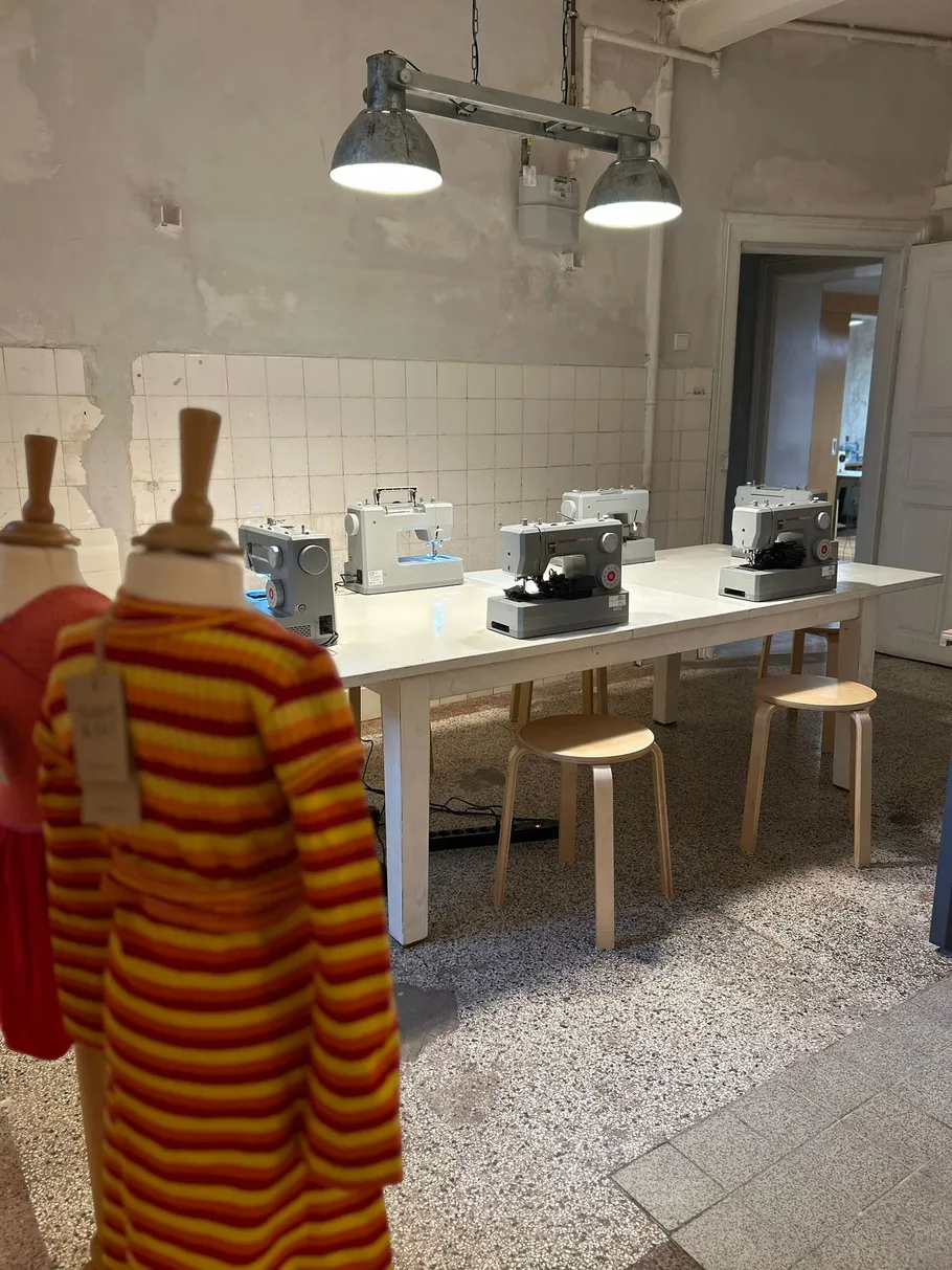 Nähmaschinen auf Tisch, Schneiderpuppen in der Nähe.