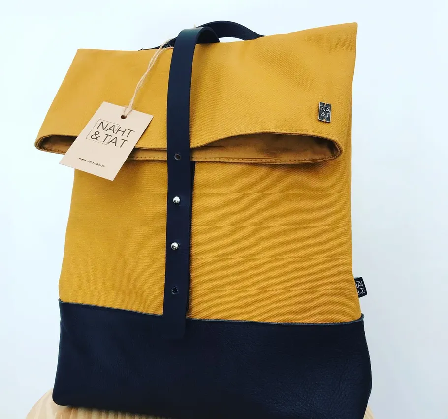 Gelber und schwarzer Rucksack mit Etikett befestigt.
