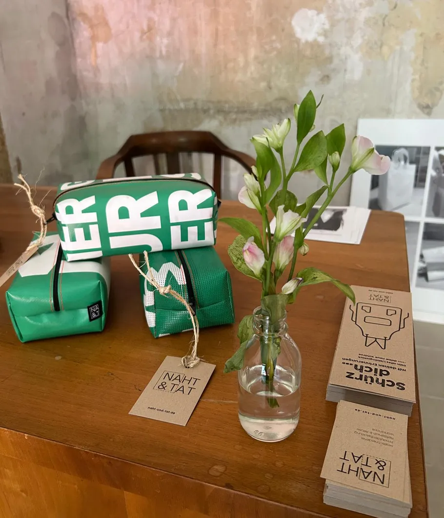Grüne Taschen und Blumen auf Holztisch.