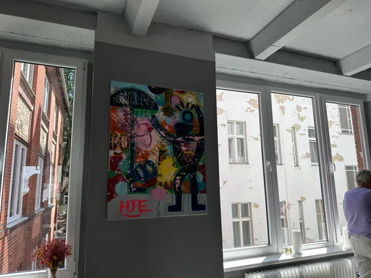 Colorful painting on wall near large windows.