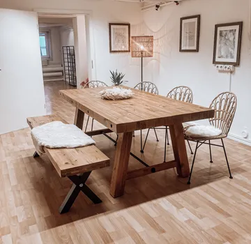 Wooden dining table with chairs in room.