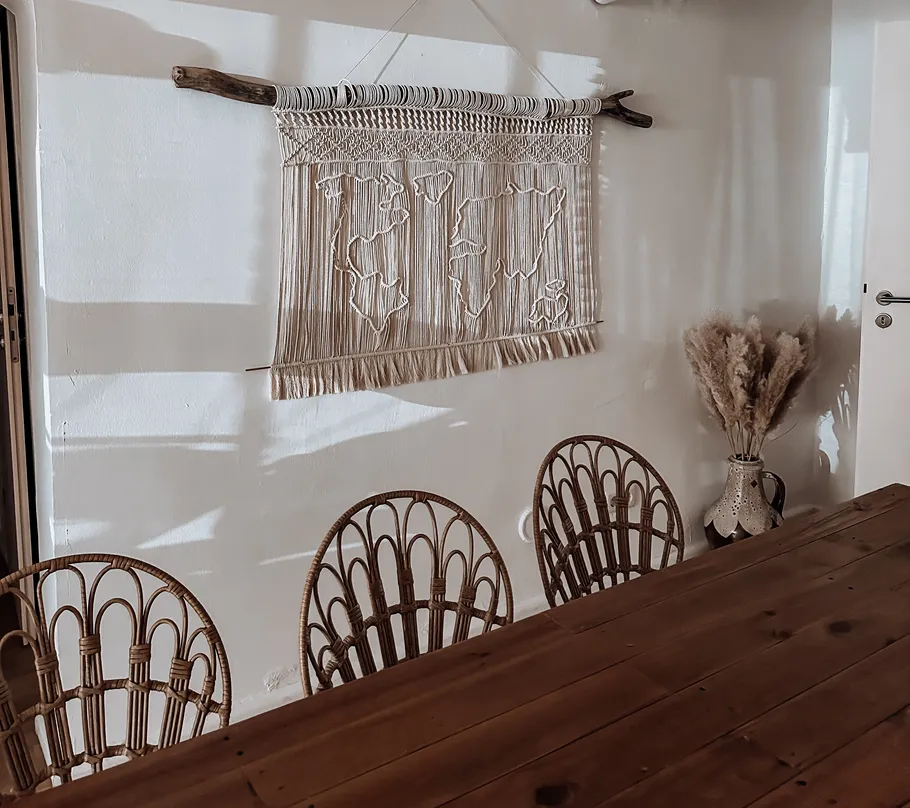 Macrame wall hanging above wooden dining table.