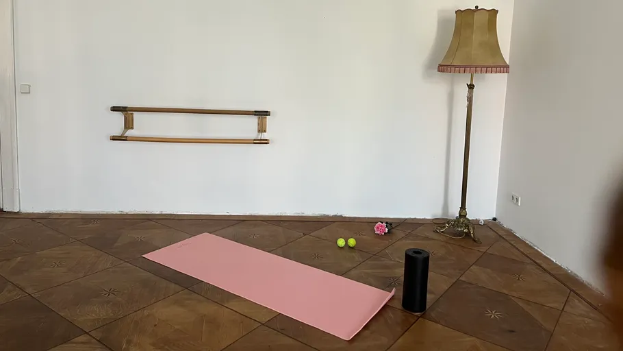 Pink yoga mat on wooden floor, near a lamp.