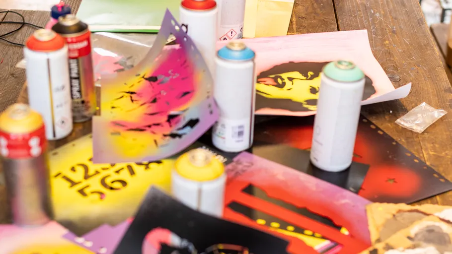 Spray paint cans with colorful stencils on table.