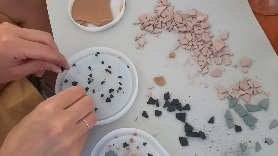 Person arranging broken tiles on table.