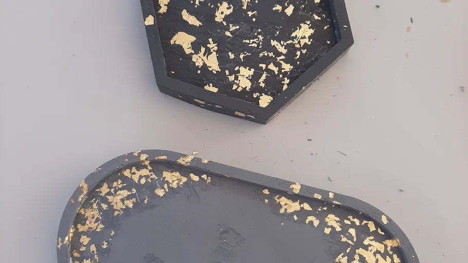Two black trays with gold flakes decoration.
