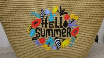 Geflochtene Tasche mit 'Hello Summer' und Blumenmuster.