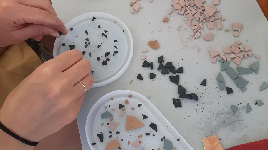 Hands arranging small tile pieces on surface.
