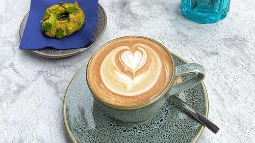 Coffee with heart art next to pastry.