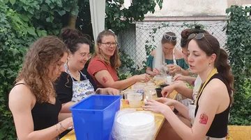 Frauen töpfern Klinker im Freien, lachen zusammen.