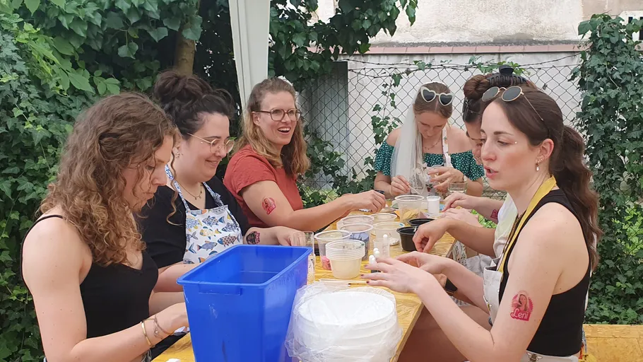 Women crafting clay pots outdoors, laughing together.