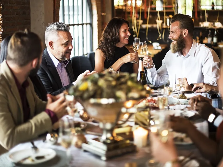 Friends toast with drinks surrounded by food.