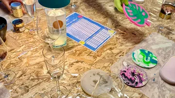 Basteltisch mit Getränken und bemalten Untersetzern.