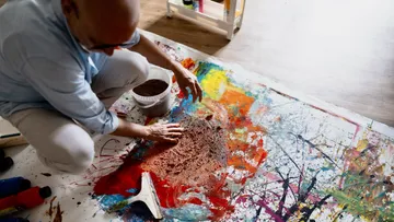 Man creating artwork on a colorful canvas.