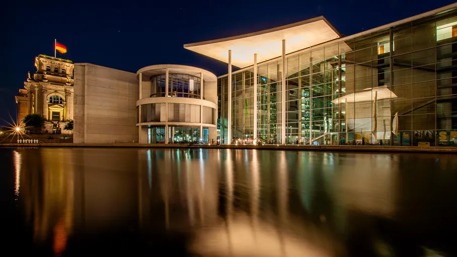 Modernes Gebäude spiegelt sich nachts im Wasser.