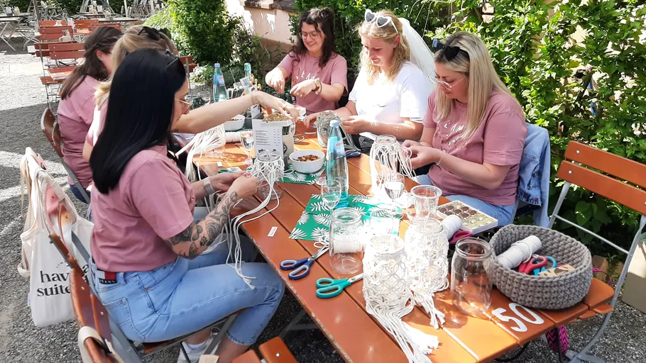 Group of women doing macramé at picnic table.