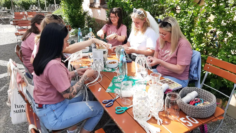 Women crafting at a wooden table outdoors.