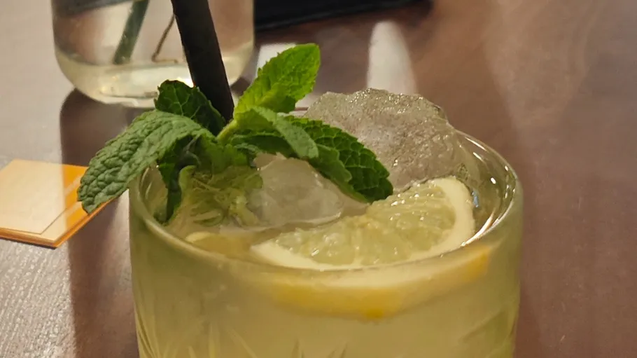 Cocktail mit Minze und Zitrone auf Tisch.