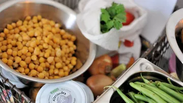 Chickpeas, vegetables, and herbs on a kitchen counter.