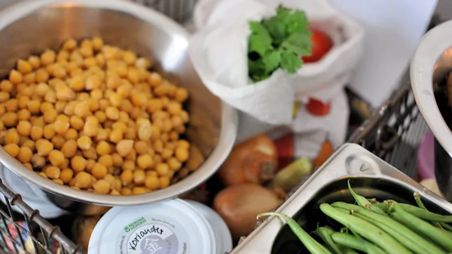 Chickpeas, vegetables, and herbs on a kitchen counter.