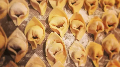 Nahaufnahme von rohen Tortellini auf bemehlter Fläche.