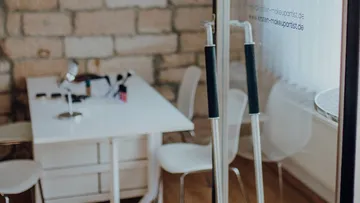 Büro mit Glastüren und weißen Möbeln.