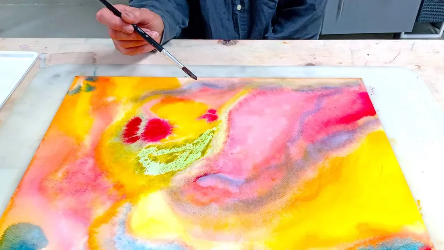 Person painting abstract art on a canvas.