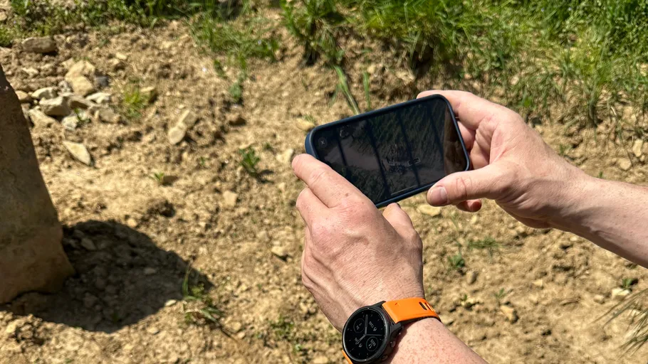 Person photographing rocky ground outdoors.